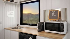 A kitchen with a sink, a coffee maker, a microwave, and a window with a view of mountains.