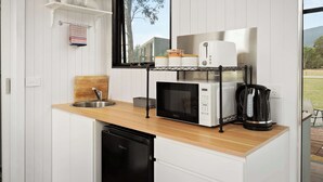 Cocina compacta con lavamanos, microondas, cafetera y ventana con vistas a zonas verdes.