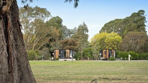 Un edificio moderno con techo plano, rodeado de un campo cubierto de césped y árboles.