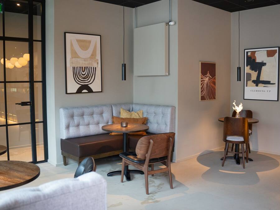 Un intérieur moderne avec un canapé gris, des tables rondes et des œuvres d’art minimalistes.