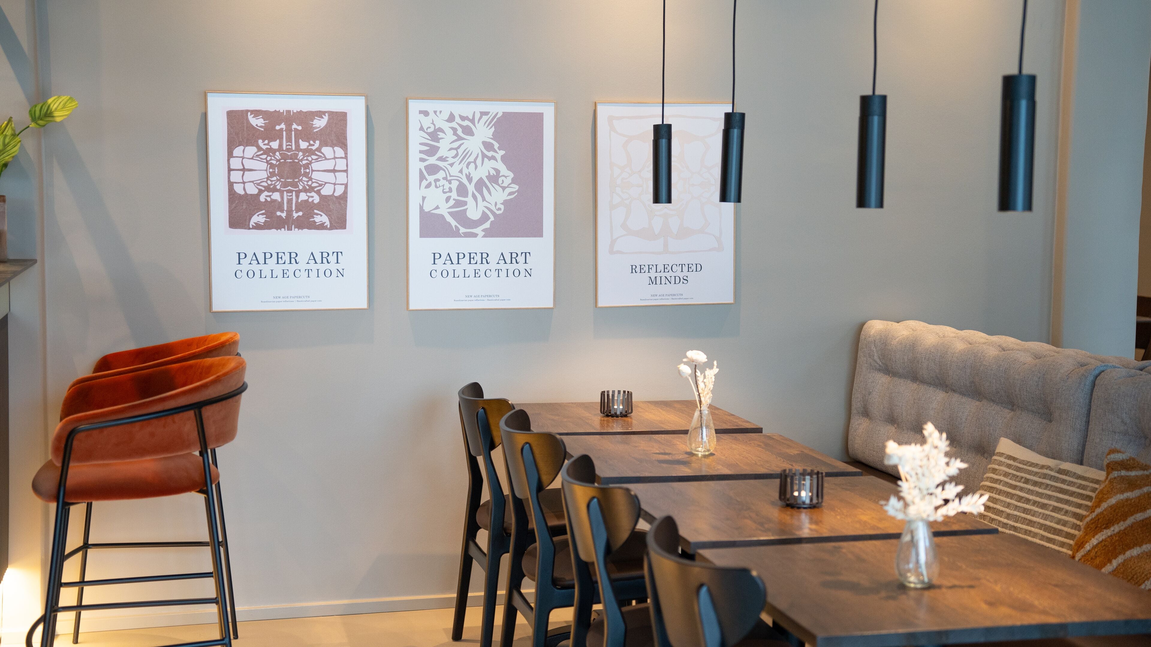 A modern dining area with a wooden table, chairs, and framed artwork on the wall.