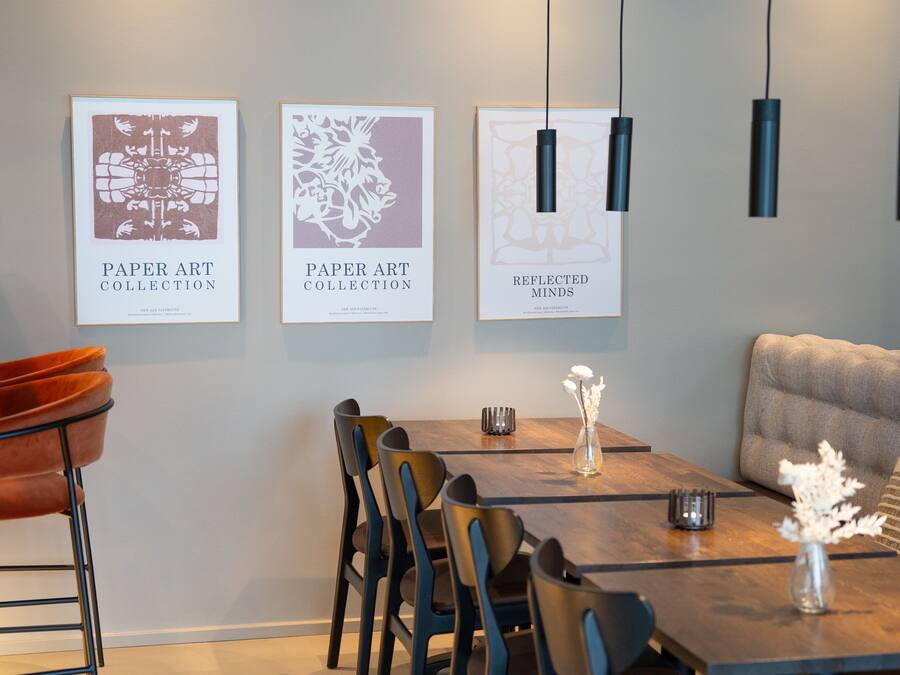 A modern dining area with a wooden table, chairs, and framed artwork on the wall.