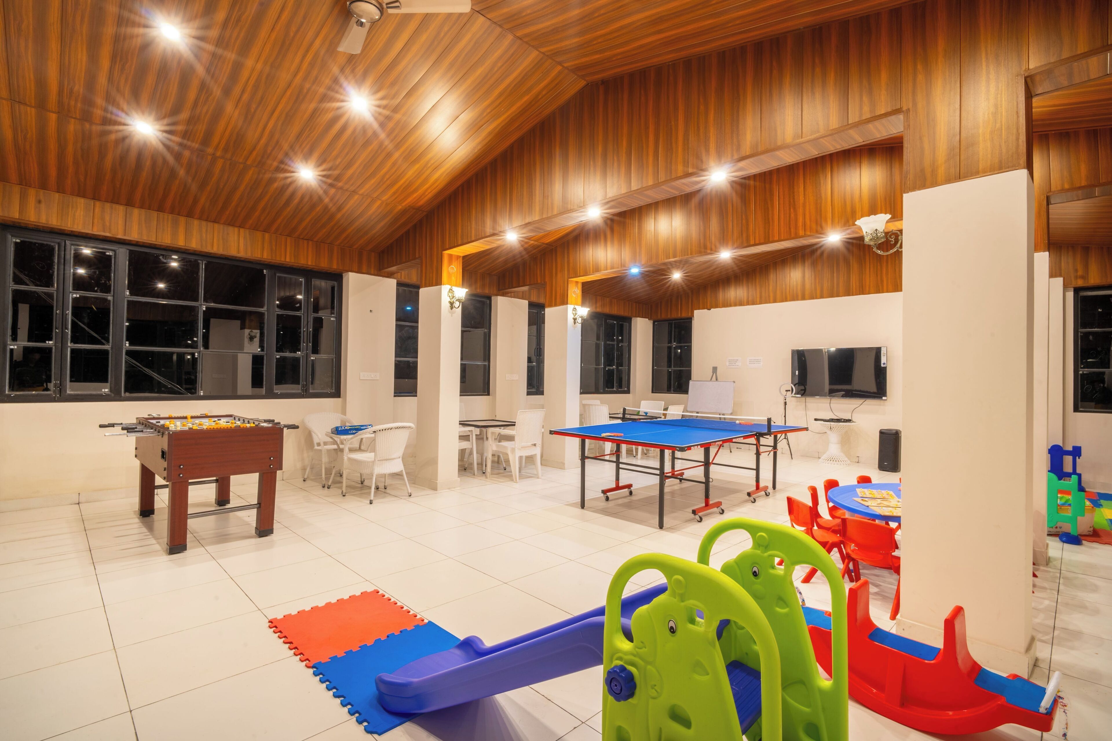 A spacious indoor play area with a foosball table, a ping pong table, and various play structures.