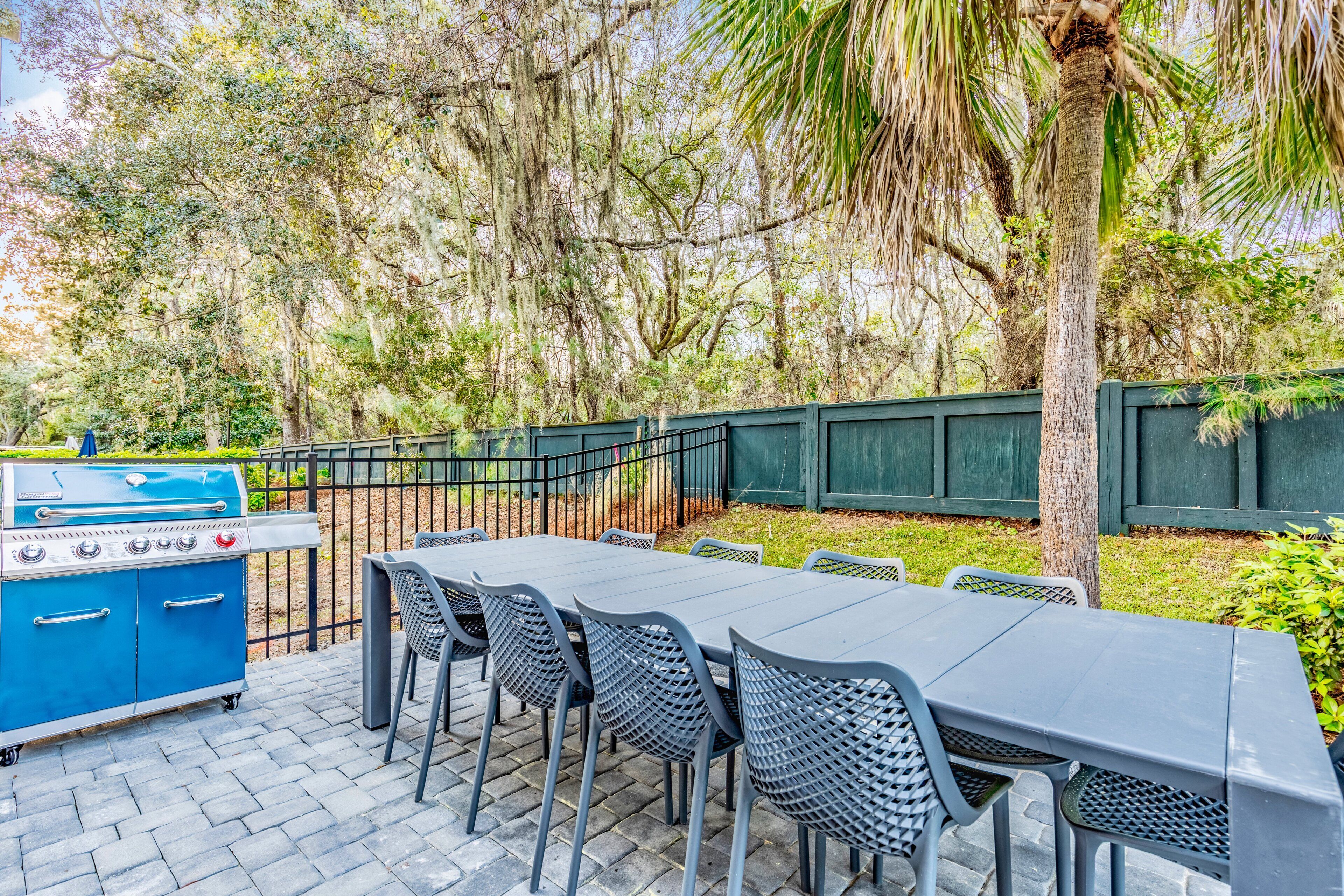 Une terrasse extérieure équipée d’un barbecue, de tables et de chaises.
