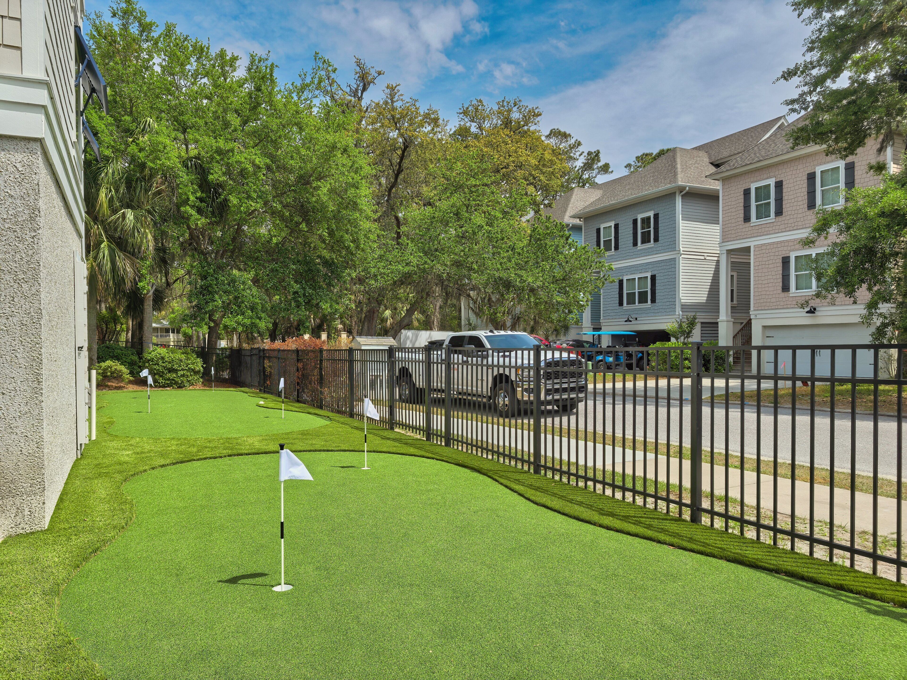 A residential area with a well-maintained lawn, a golf flag, and houses in the background.
