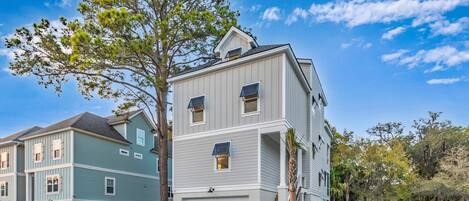 A two-story residential building with a garage, a covered front porch, and a staircase leading to the second floor.