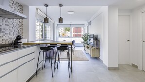 Una cocina moderna con una isla grande, taburetes de bar y vistas al exterior.
