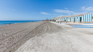 Un hotel frente a la playa con una extensa playa de arena y una hilera de edificios blancos y azules a rayas.