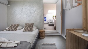 Een moderne slaapkamer met een bed, nachtkastje en een badkamer met een houten wastafel en wastafel.