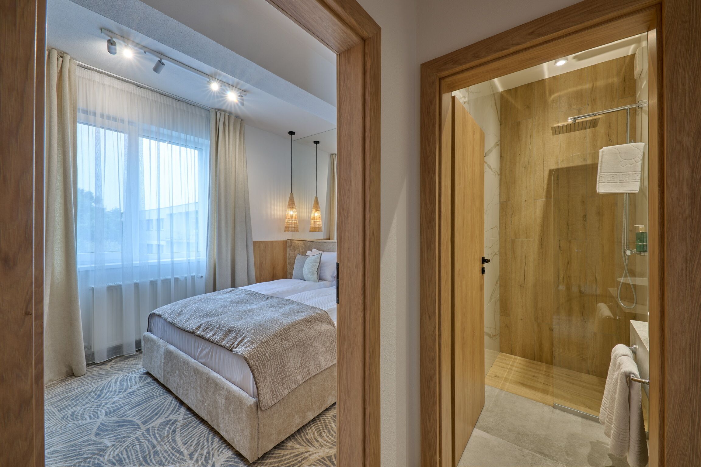A hotel room with a bed, a shower, and a view of the city.