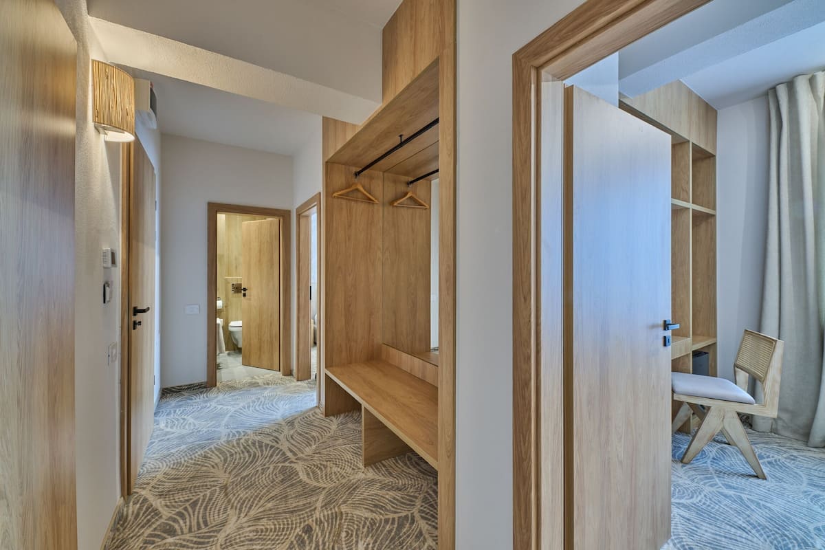A modern hotel room with a wooden wardrobe, a bench, and a chair.
