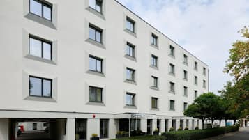 Un hotel moderno con fachada blanca, múltiples ventanales y un cartel que dice 'Hotel Serenity by Banco'.