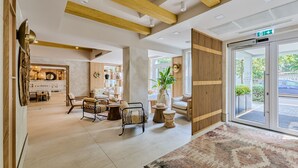 A spacious lobby with a wooden reception desk, comfortable seating areas, and a large patterned rug. - Serenity Hotel (Timisoara)