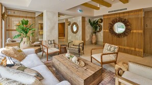A spacious lobby with a wooden coffee table, comfortable seating, and decorative elements like plants and mirrors. - Serenity Hotel (Timisoara)