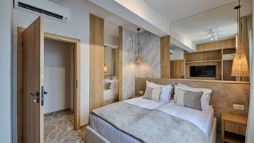 Ein modernes Hotelzimmer mit einem großen Bett, Holzvertäfelung, einer Wand aus Marmor, einem Fernseher und einer Pendelleuchte.