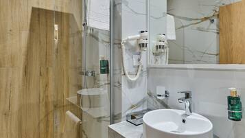 A modern bathroom with a glass-enclosed shower, a marble-tiled wall, and a wooden accent panel.