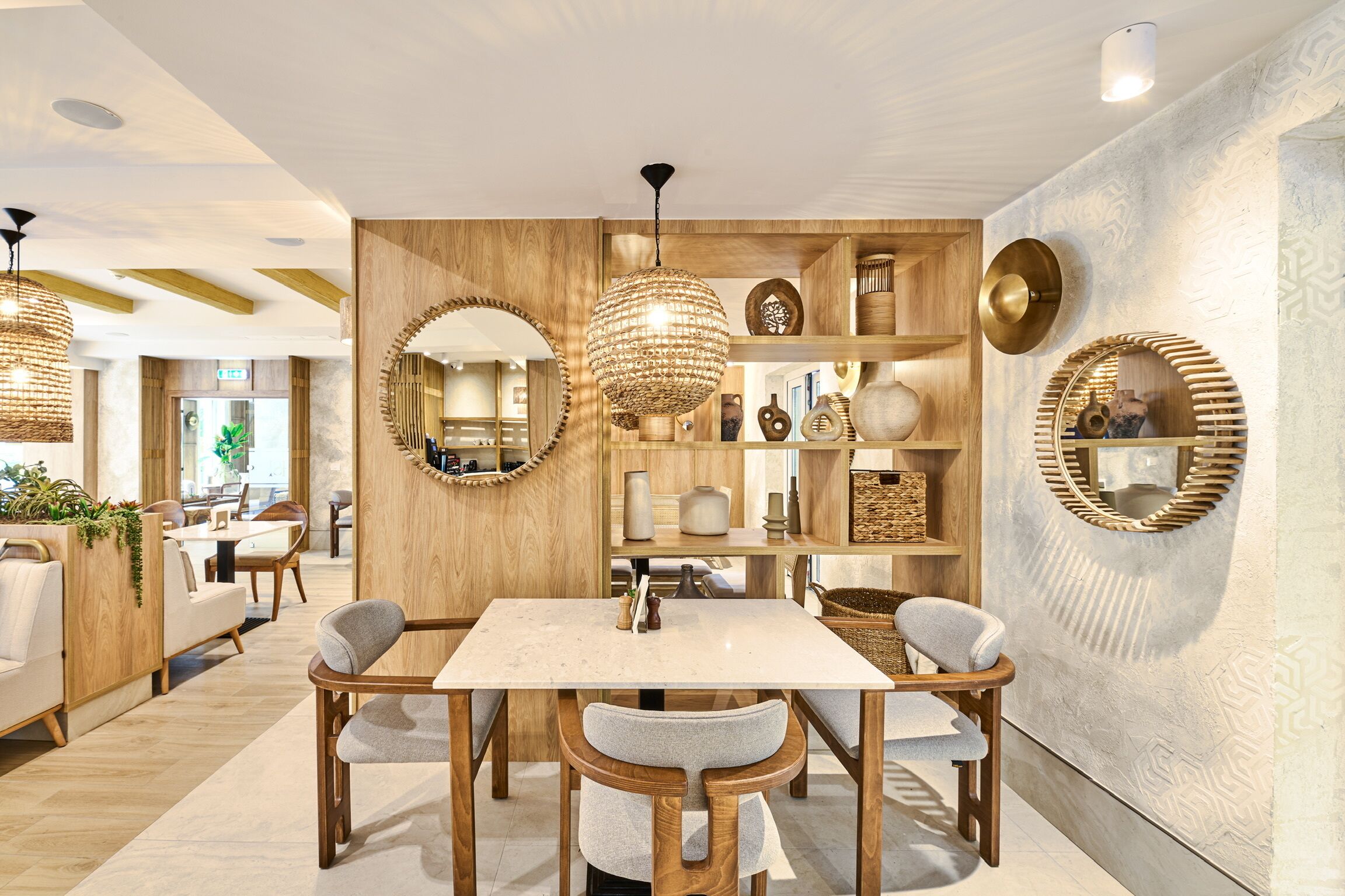 A modern dining area with a wooden table and chairs, surrounded by shelves with decorative items.