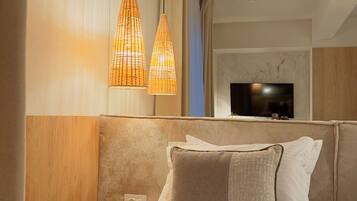 A hotel room with a bed, a nightstand, a TV, and a wall-mounted light fixture.