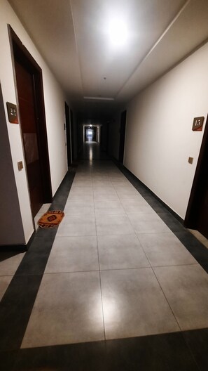 A long, narrow hallway with a tiled floor, doors on both sides, and a light at the end. - Luxury Apartment in Islamabad (Islamabad)