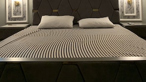 A modern hotel room with a large bed, a geometric headboard, and a central air conditioning unit. - Luxury Apartment in Islamabad (Islamabad)