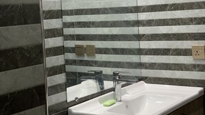 A bathroom with a white sink, a mirror, and a towel hanging on the wall. - Luxury Apartment in Islamabad (Islamabad)