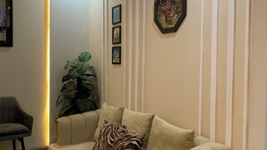 A beige sofa with a zebra-patterned pillow, a potted plant, and framed artwork on the wall. - Luxury Apartment in Islamabad (Islamabad)