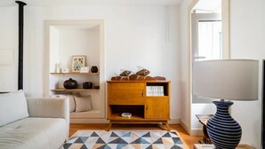 Un soggiorno moderno con un divano, un mobile in legno con oggetti decorativi, un tappeto a motivi e una lampada.
