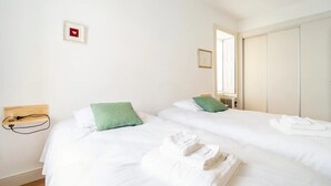 Una camera d'albergo con due letti, una testiera in legno, un comodino con una lampada, un quadro appeso al muro e una finestra con vista all'esterno.
