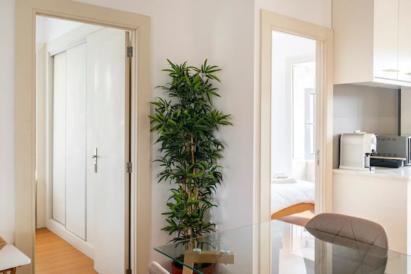 A modern hotel room with a glass table, a large green plant, and a bed with white bedding. - Varanda Para o Mar (Esmoriz)