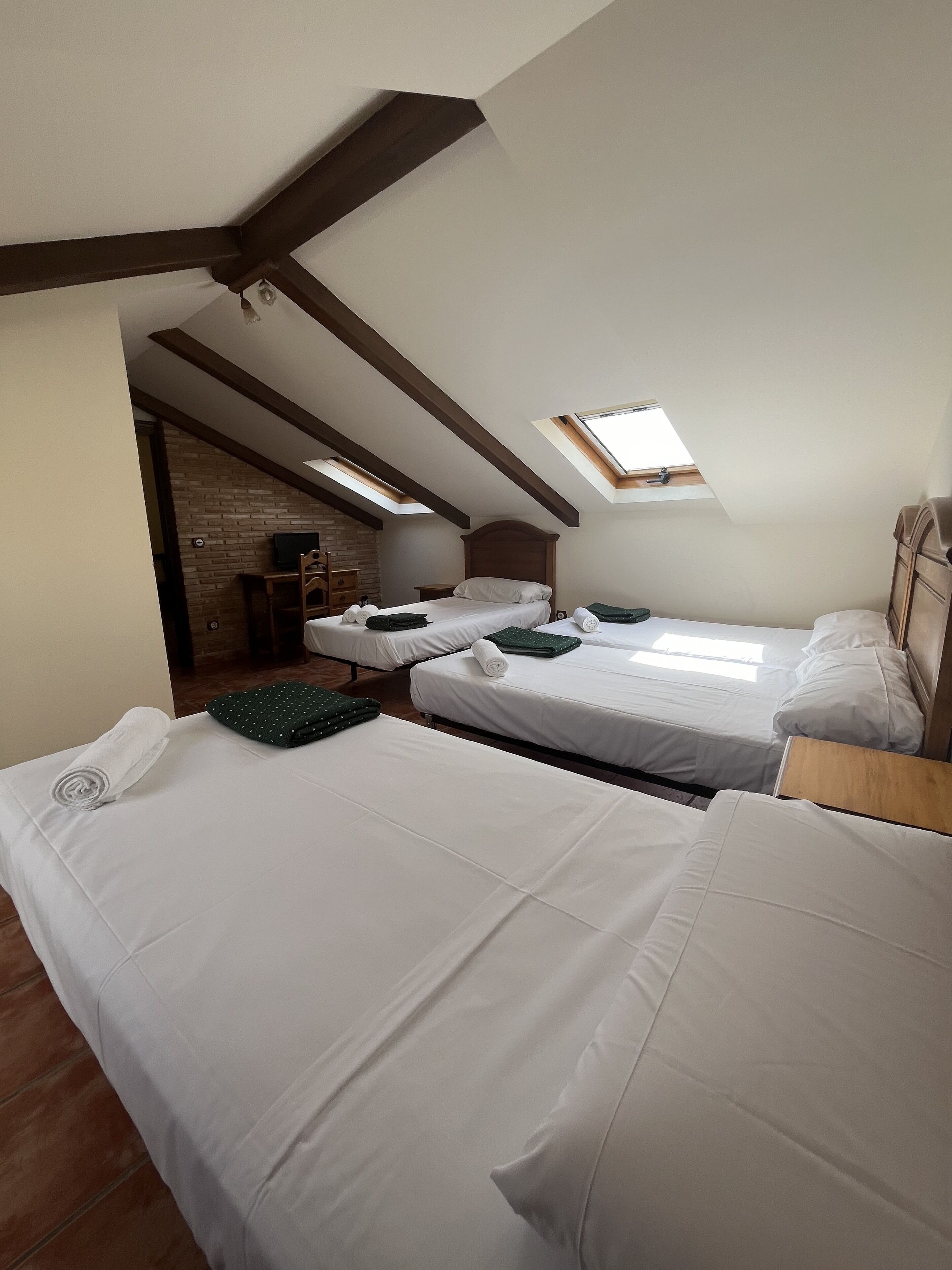 Una habitación con dos camas, un tragaluz y una pared de ladrillo.