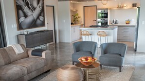 Un grand espace de vie comprenant un canapé, des fauteuils, une table basse et une cuisine à l’arrière-plan.