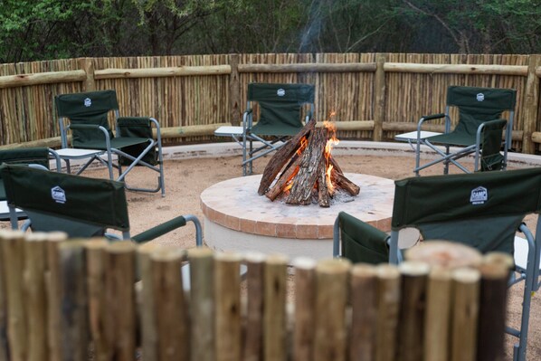 A circular seating area with a central fire pit surrounded by green folding chairs.