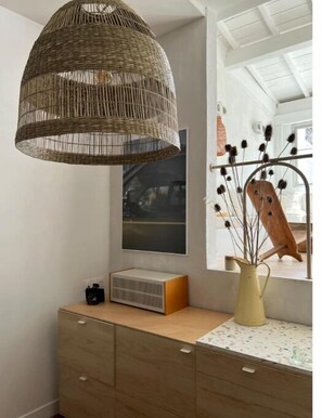 Cozy retreat with a woven wicker pendant light, wooden dresser, and large window.
