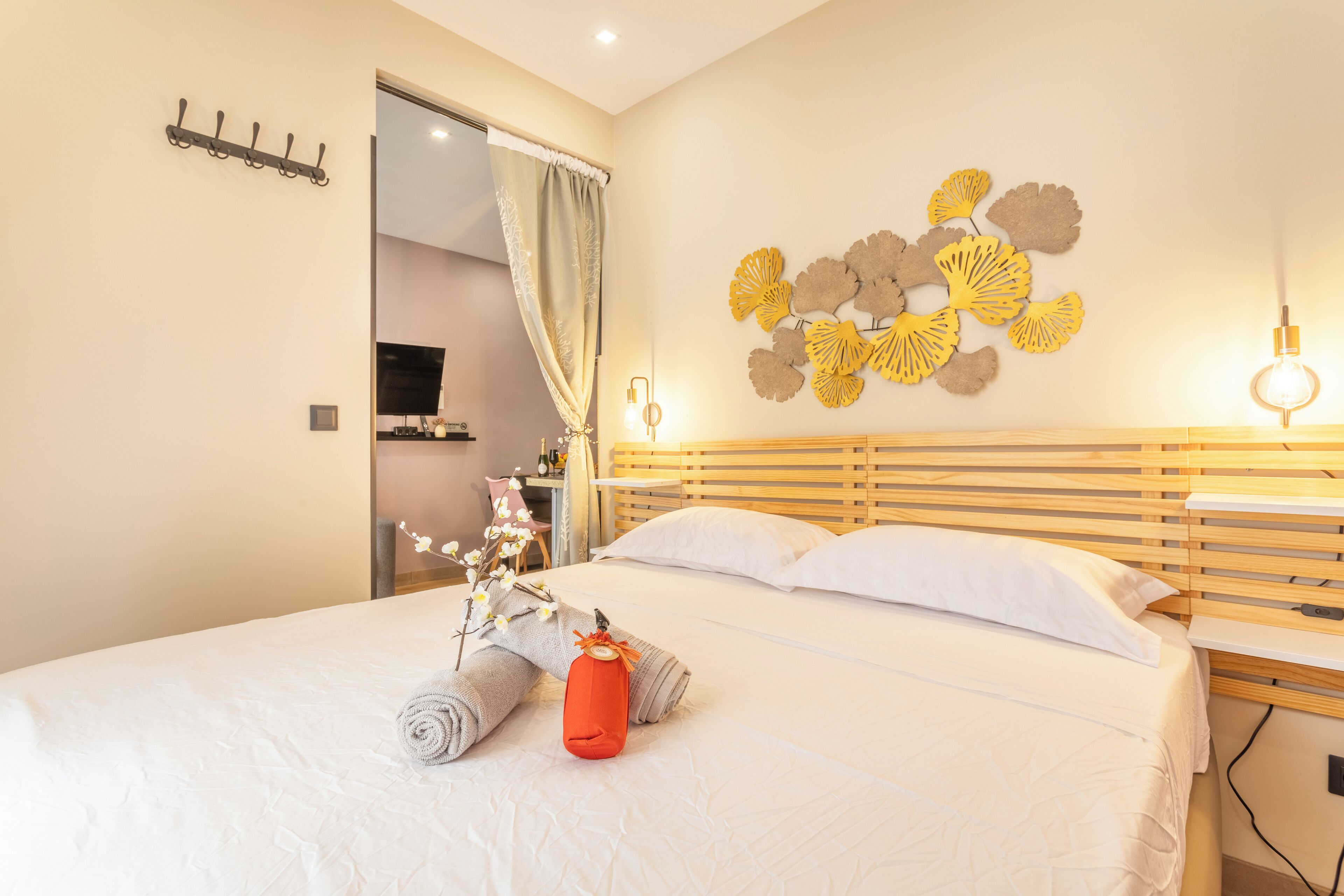 A hotel room with a neatly made bed, a wall-mounted light fixture, and a decorative wall art piece.