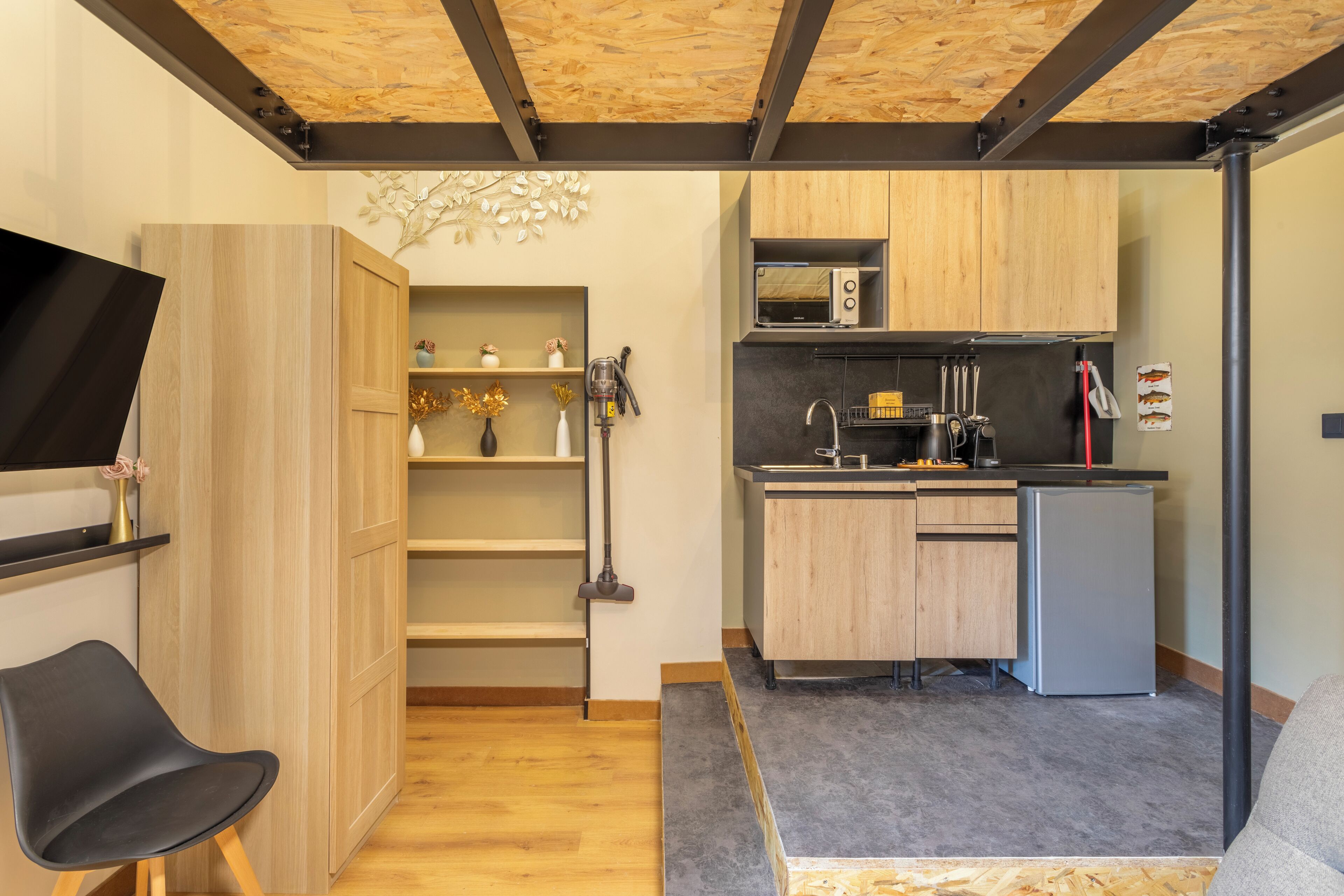 A compact kitchen with wooden cabinets, a microwave, and a refrigerator.