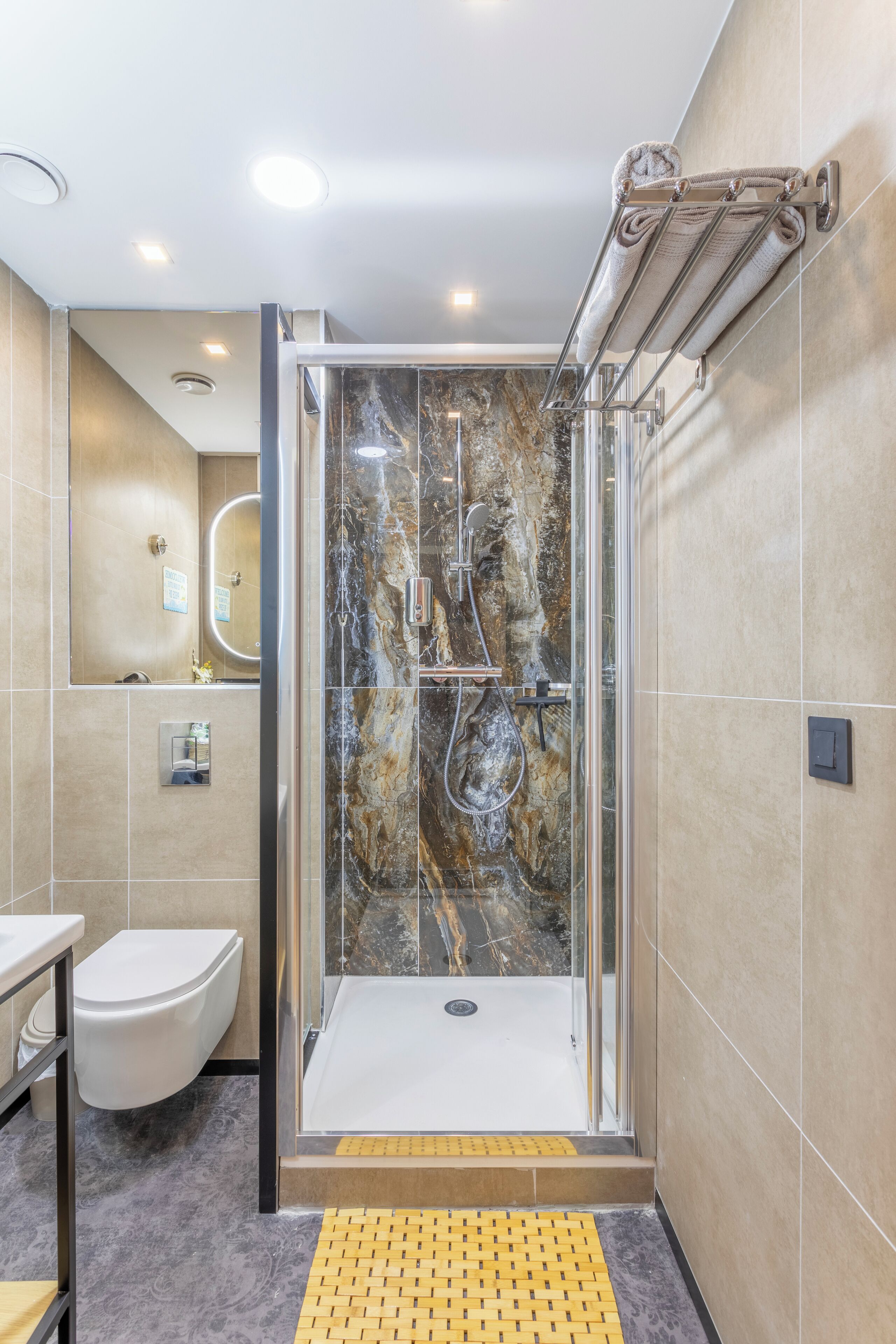 A modern bathroom with a glass-enclosed shower, a toilet, and a sink.