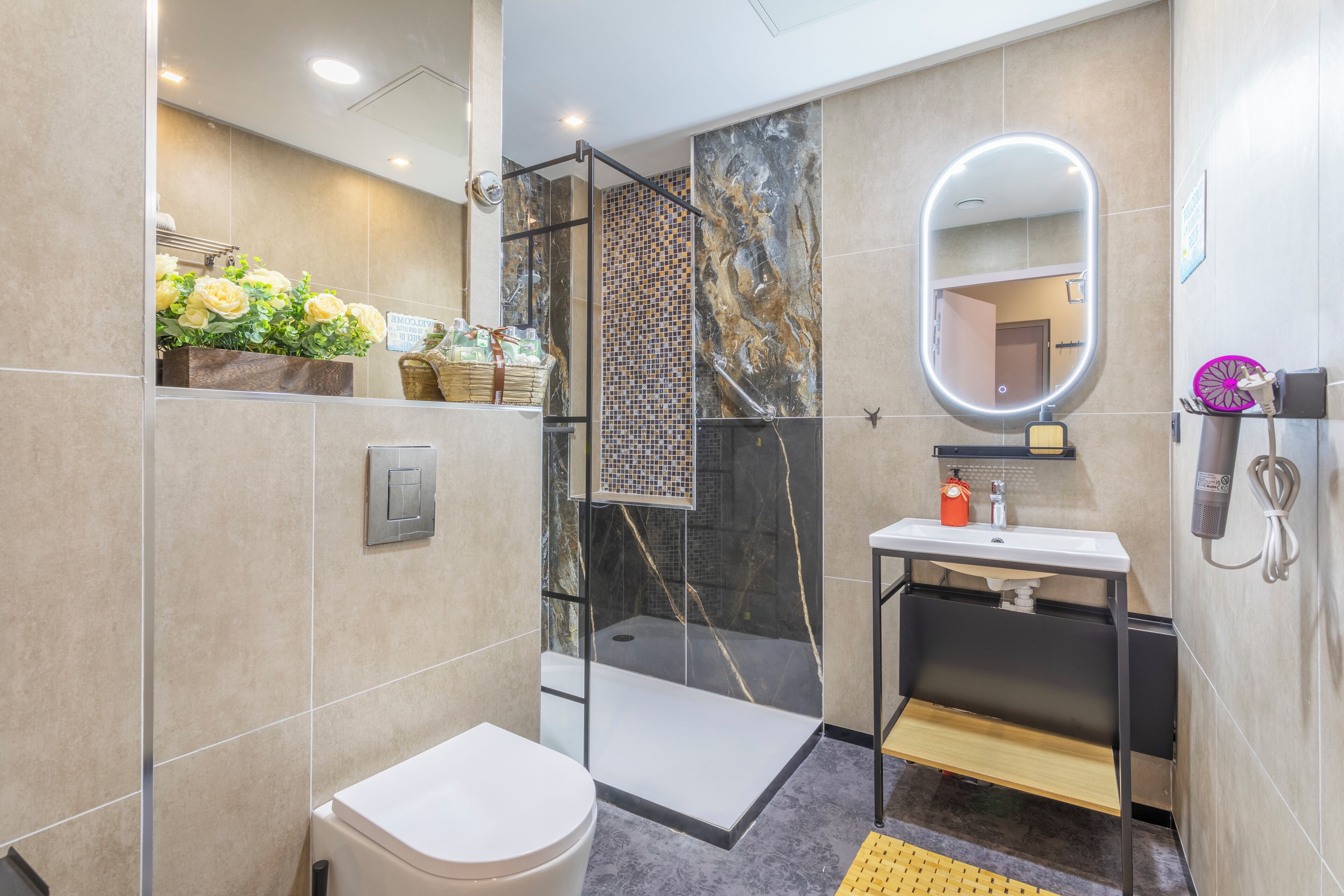 A modern bathroom with a glass-enclosed shower, a white toilet, a vanity with a mirror, and a small sink.