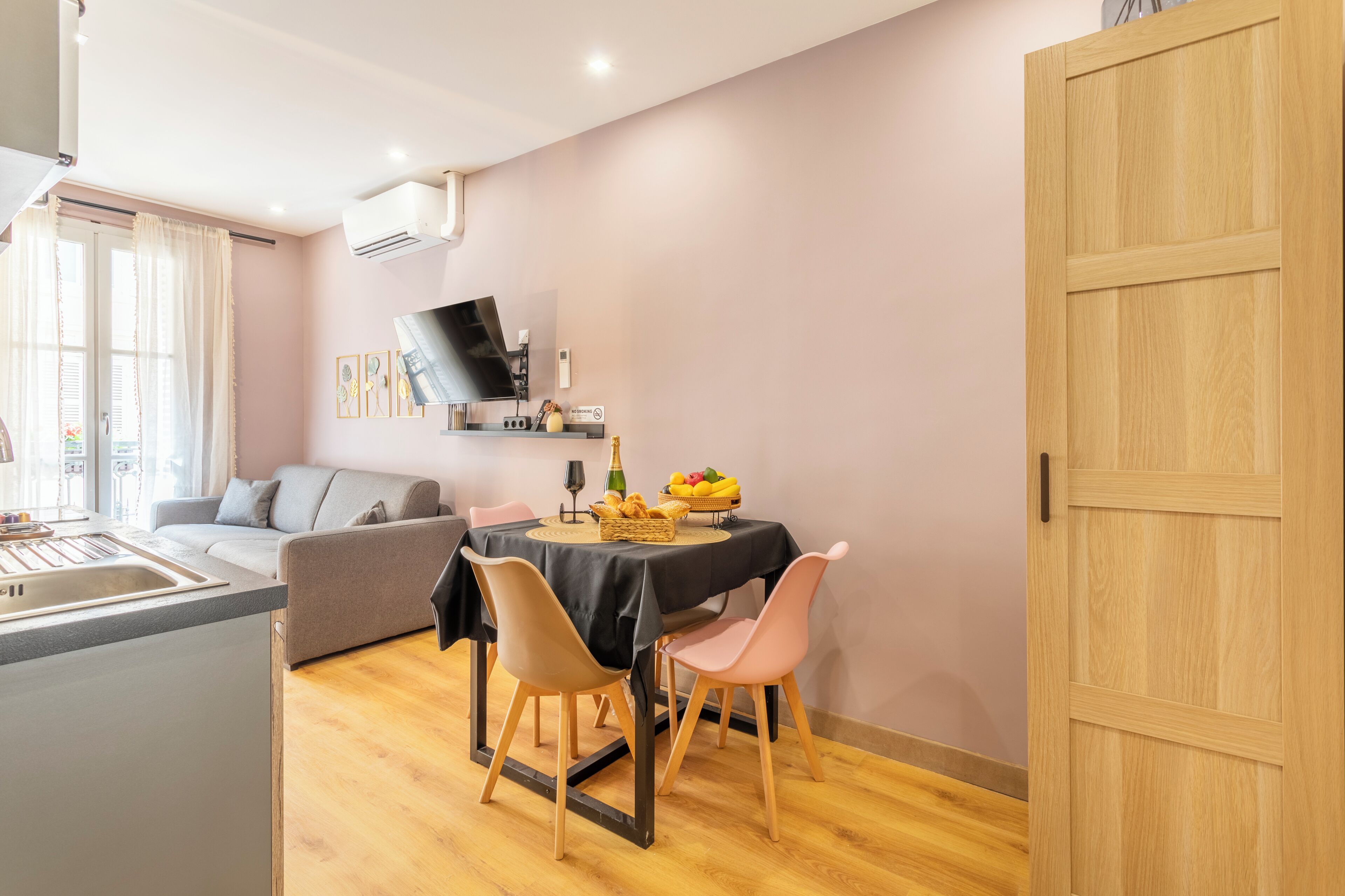 A compact living space with a kitchenette, a dining area with a table and chairs, a sofa, and a wooden wardrobe.
