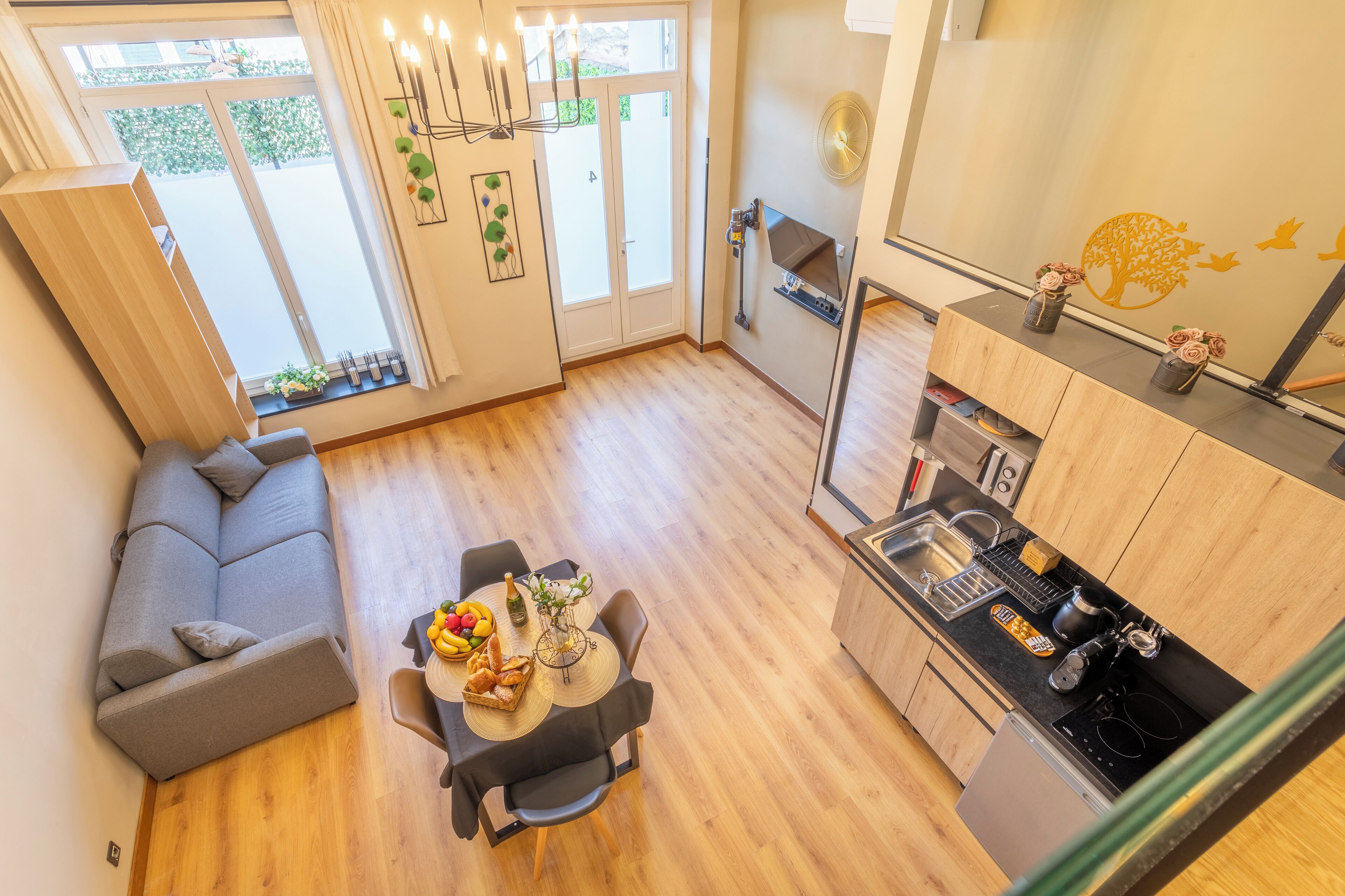 A modern living space with a dining area, kitchen, and a gray sofa.