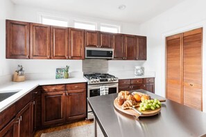 Una cocina moderna con armarios de madera oscura, encimeras de acero inoxidable, estufa a gas y microondas.