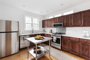 A modern kitchen with wooden cabinets, stainless steel appliances, and a central island.