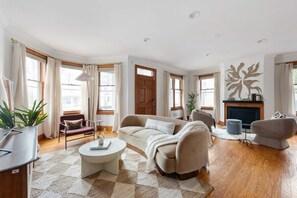 A spacious living room with a sofa, armchairs, a coffee table, and a fireplace.