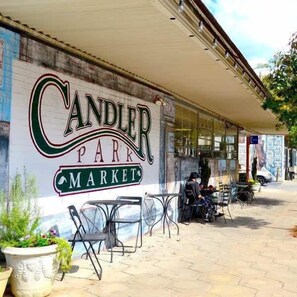 A storefront with a sign reading "CANDLER PARK MARKET" and outdoor seating.