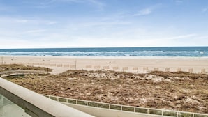 Une plage avec un rivage sablonneux, une clôture en bois et une promenade en planches menant à la plage.