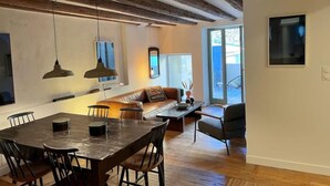 A modern kitchen with a wooden dining table and chairs, a built-in oven, and pendant lights. - Spacieux 2 Chambres Dans le Centre D'arles Avec Terrasse (Arles)