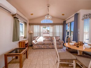 Ein gemütliches Wohnzimmer mit einer Couch, einem Esstisch und einer Chandelier.