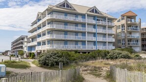 A multi-story hotel with balconies, located near a beach.
