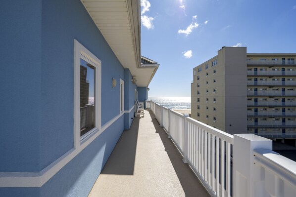 A balcony with a view of the ocean and a building in the background. - Luxury Awaits Your Family in This Stunning Sideview Oceanfront Property (Ocean City)