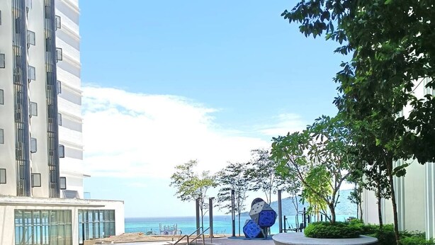 A modern pool area with a wooden deck, a curved pool edge, and a view of the sea. - Covesign Suite, The Shore Kota Kinabalu (Kota Kinabalu)