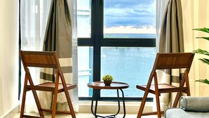 A room with two wooden chairs facing a large window overlooking a body of water. - Covesign Suite, The Shore Kota Kinabalu (Kota Kinabalu)